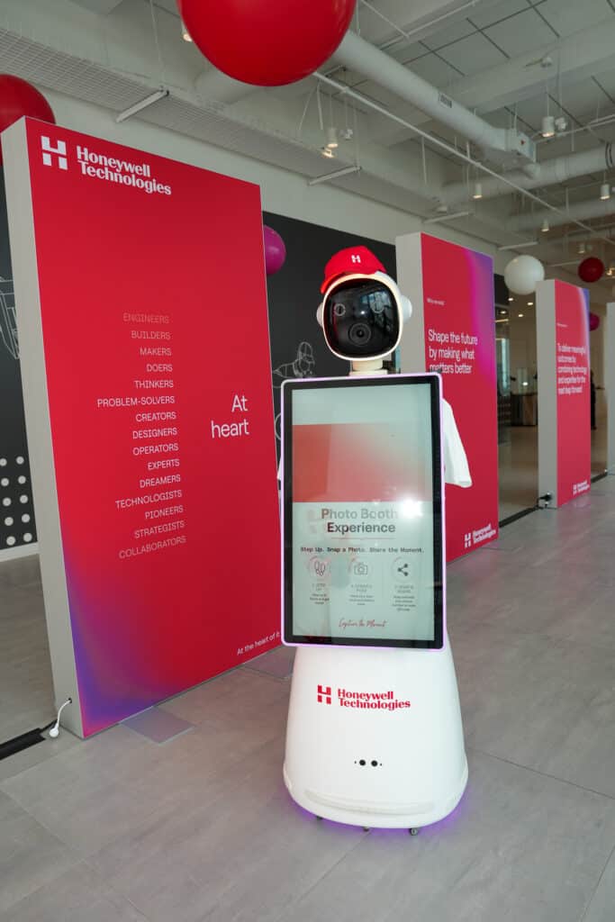 AI robot photo booth kiosk with digital display set up against a red branded backdrop in Charlotte, NC