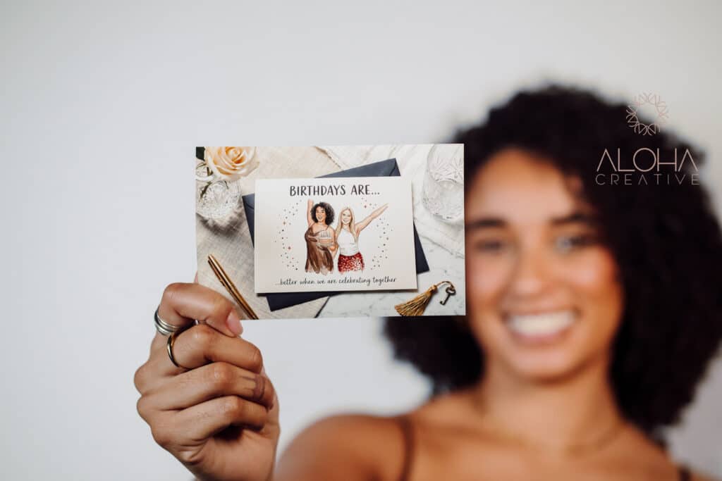 Guest holding out a printed birthday card with an illustrated AI portrait of two friends from a photo booth in Charlotte, NC