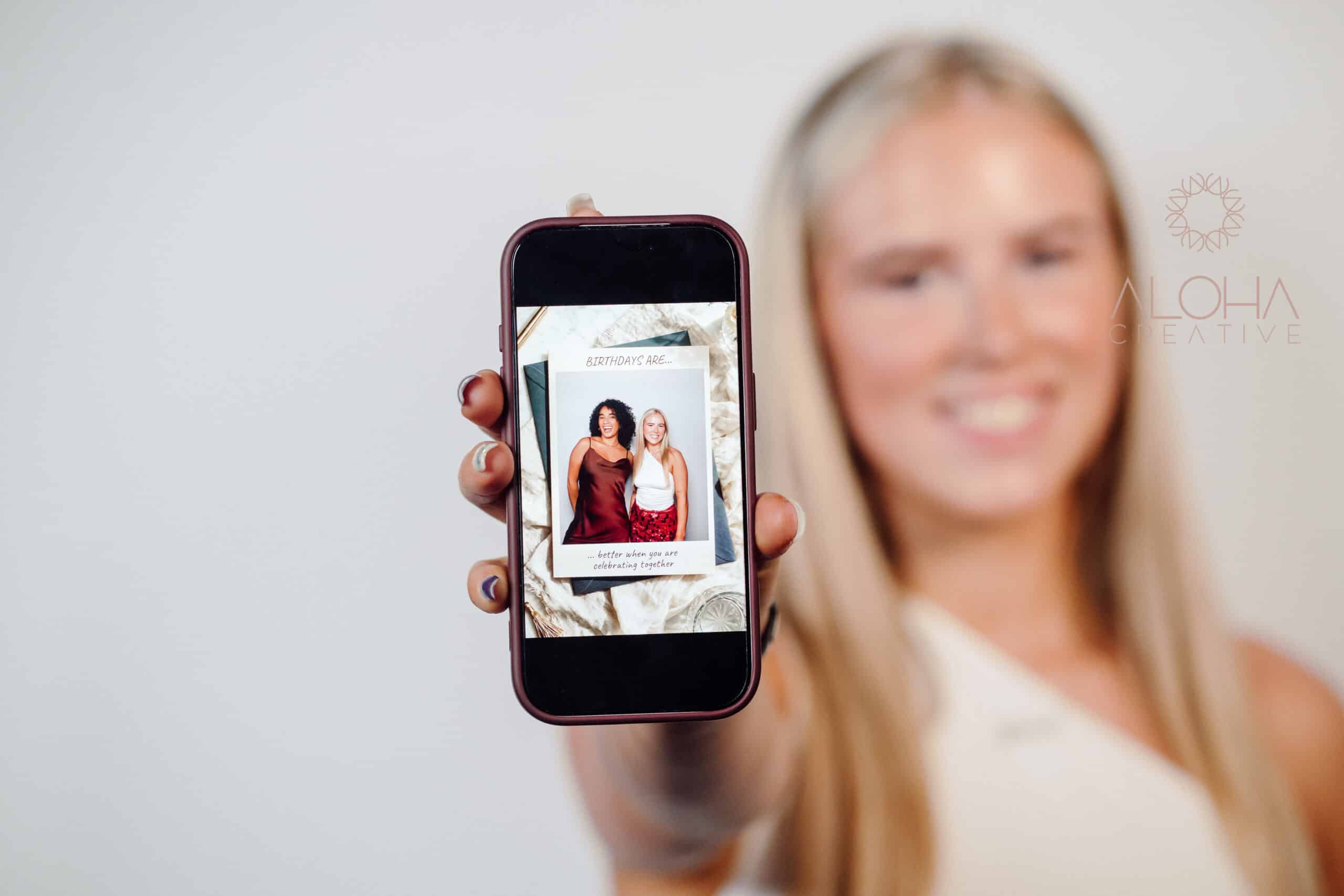 Smiling guest holding up her phone with a birthday party photo delivered instantly from a digital selfie photo booth in Charlotte, NC
