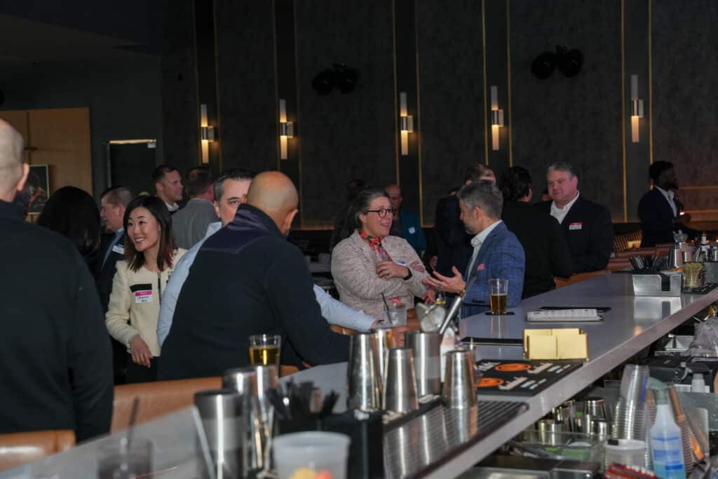 Networking event scene with diverse attendees engaging in conversation at a stylish bar, showcasing authentic interactions and event atmosphere.
