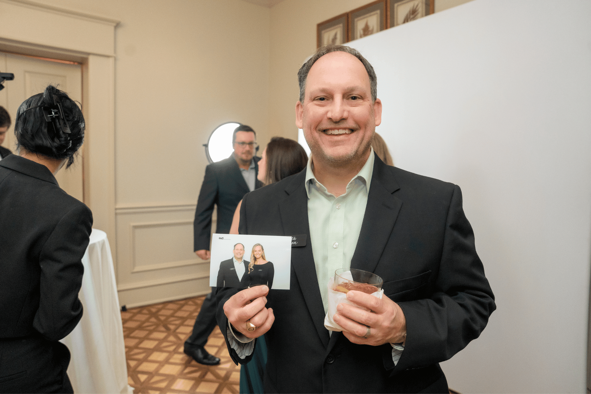 Corporate gala guest holding a branded photo print from Aloha Creative's premium photo booth rental at a Tega Cay luxury event